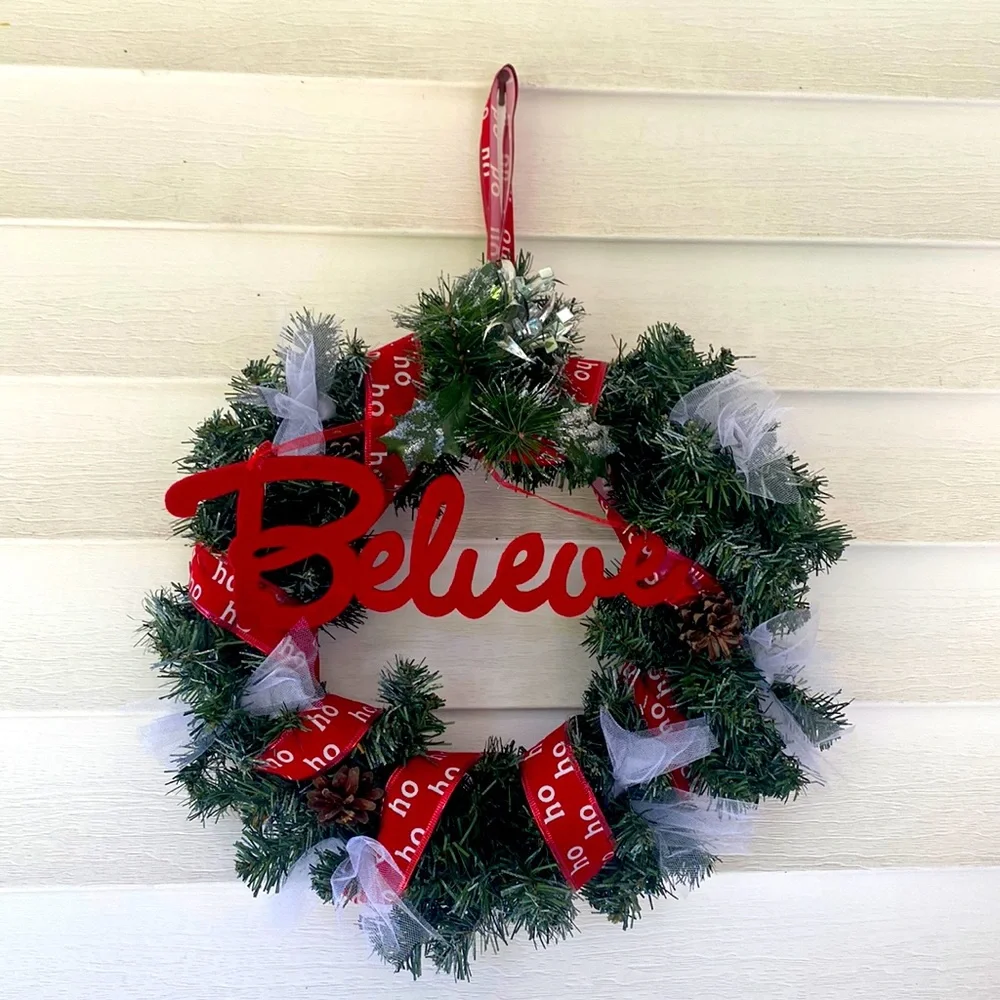 Believe evergreen faux wreath trimmed with the word believe and ho ho ho ribbon